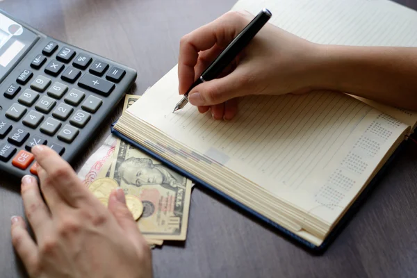 Akuntan menghitung keuntungan - foto close-up dari tangan menghitung koin dan membuat catatan di atas kertas. Makro dengan fokus kabur dan lembut . — Stok Foto