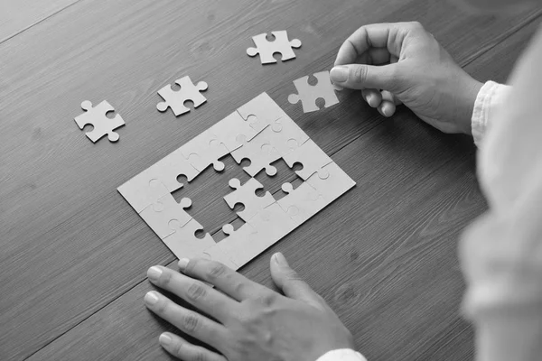 Image of businesswoman connecting elements of white puzzle