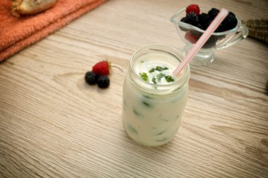 Yaz kokteyl ve ahşap bir masa üzerinde çilek ile bir fincan tabağı.