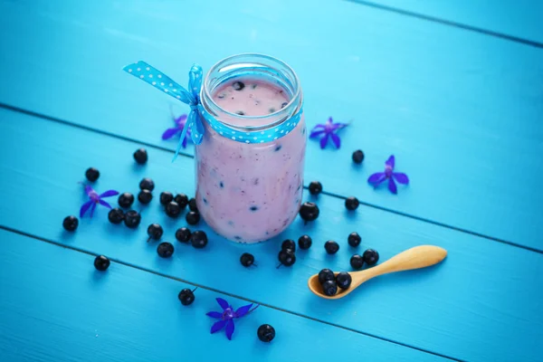 Iogurte com mirtilos frescos inteiros e farinha de aveia na mesa de madeira azul. — Fotografia de Stock