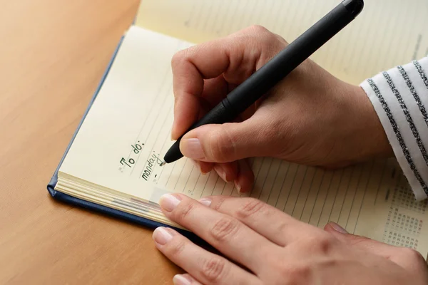 Žena ruce s perem psaní na notebook — Stock fotografie