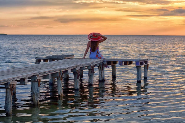 Девочка в морском стиле сидит на деревянном мостике. Путешествие и отпуск. Концепция свободы . — стоковое фото