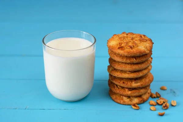 A glass of milk, homemade cakes (oatmeal cookies with nuts)  on a blue wooden background.
