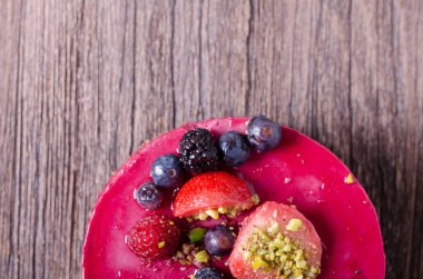 Taze çilek, ahududu, yaban mersini, kuş üzümü ve ahşap zemin üzerine Antep fıstığı ile lezzetli frambuazlı pasta. metniniz için boş alan.