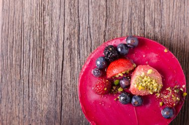 Taze çilek, ahududu, yaban mersini, kuş üzümü ve ahşap zemin üzerine Antep fıstığı ile lezzetli frambuazlı pasta. metniniz için boş alan.