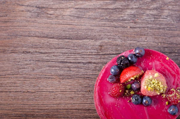 Taze çilek, ahududu, yaban mersini, kuş üzümü ve ahşap zemin üzerine Antep fıstığı ile lezzetli frambuazlı pasta. metniniz için boş alan.