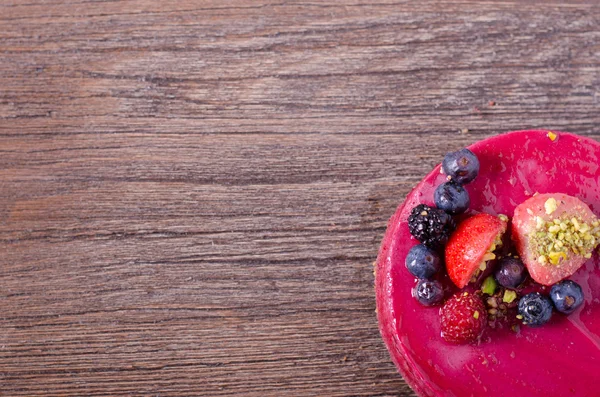 Taze çilek, ahududu, yaban mersini, kuş üzümü ve ahşap zemin üzerine Antep fıstığı ile lezzetli frambuazlı pasta. metniniz için boş alan.