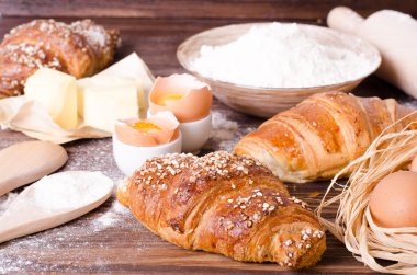 Malzemeler kruvasan - kağıt, un, tahta kaşık, oklava, yumurta pişirme için yumurta sarısı, tereyağı bir rustik ahşap tepsi masaya servis. 