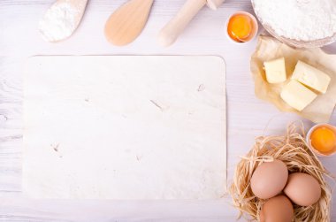 Kruvasan pişirme için Malzemeler - kağıt, un, tahta kaşık, oklava, yumurta, yumurta sarısı, tereyağı beyaz arka plan üzerinde servis.