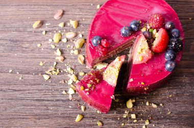 Taze çilek, ahududu, yaban mersini, kuş üzümü ve ahşap zemin üzerine Antep fıstığı ile lezzetli frambuazlı pasta. 