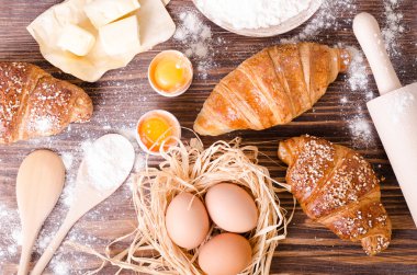 Malzemeler kruvasan - kağıt, un, tahta kaşık, oklava, yumurta pişirme için yumurta sarısı, tereyağı bir rustik ahşap tepsi masaya servis. 