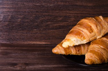 Taze kruvasanlar ahşap arka plan üzerinde. Metniniz için boş alan.