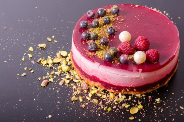 Taze çilek, ahududu, yaban mersini, kuş üzümü ve siyah arka plan üzerine Antep fıstığı ile lezzetli frambuazlı pasta. 