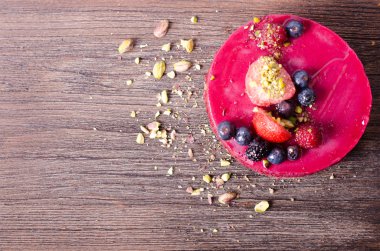 Taze çilek, ahududu, yaban mersini, kuş üzümü ve ahşap zemin üzerine Antep fıstığı ile lezzetli frambuazlı pasta. metniniz için boş alan.