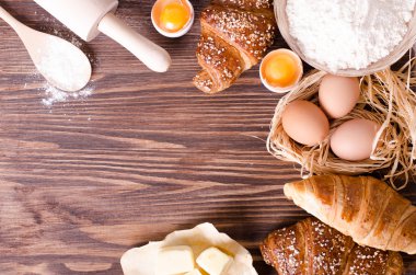 Malzemeler kruvasan - kağıt, un, tahta kaşık, oklava, yumurta pişirme için yumurta sarısı, tereyağı bir rustik ahşap tepsi masaya servis. 