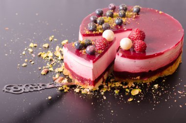 Taze çilek, ahududu, yaban mersini, kuş üzümü ve kürek, siyah zemin üzerine Antep fıstığı ile lezzetli frambuazlı pasta parçası. Metniniz için boş alan.