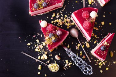 Taze çilek, ahududu, yaban mersini, kuş üzümü ve siyah arka plan üzerine Antep fıstığı ile lezzetli frambuazlı pasta parçaları. Metniniz için boş alan.