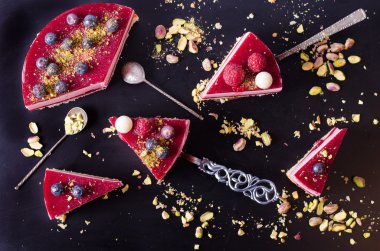 Taze çilek, ahududu, yaban mersini, kuş üzümü ve siyah arka plan üzerine Antep fıstığı ile lezzetli frambuazlı pasta parçaları. Metniniz için boş alan.