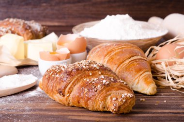 Malzemeler kruvasan - kağıt, un, tahta kaşık, oklava, yumurta pişirme için yumurta sarısı, tereyağı bir rustik ahşap tepsi masaya servis. 