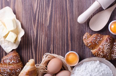 Malzemeler kruvasan - kağıt, un, tahta kaşık, oklava, yumurta pişirme için yumurta sarısı, tereyağı bir rustik ahşap tepsi masaya servis. 