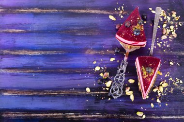 Taze ahududu, yaban mersini, kuş üzümü ve kürek, parlak mor, mavi arka plan antep fıstığı ile lezzetli ahududu kek Parçaları. Metniniz için boş alan.