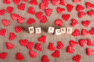 Ahşap küpleri ve çul, tuval arka plan üzerinde kırmızı birçok dekoratif kalpler aşkım kelime. Vintage tarzı.  
