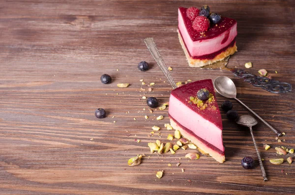 Stuk heerlijke frambozen cake met verse frambozen, bosbessen, krenten en pimpernoten (pistaches) op de schop, houten achtergrond. Vrije ruimte voor uw tekst. — Stockfoto