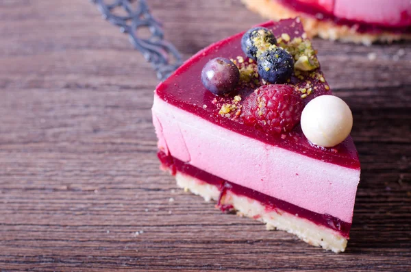 Heerlijke frambozen taart met verse aardbeien, frambozen, bosbessen, krenten en pistachenoten op houten achtergrond. — Stockfoto