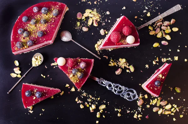 Taze çilek, ahududu, yaban mersini, kuş üzümü ve siyah arka plan üzerine Antep fıstığı ile lezzetli frambuazlı pasta parçaları. Metniniz için boş alan.