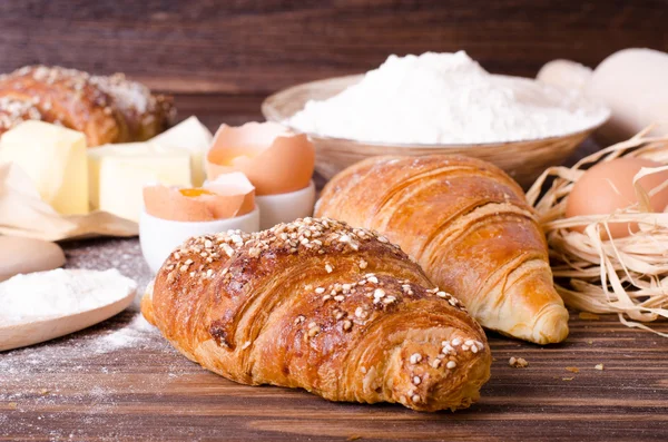 Malzemeler kruvasan - kağıt, un, tahta kaşık, oklava, yumurta pişirme için yumurta sarısı, tereyağı bir rustik ahşap tepsi masaya servis. 
