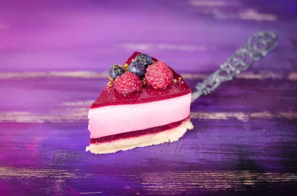 Кусок вкусного малинового пирога со свежей малиной, черникой, смородиной и фисташками на лопате, ярко-фиолетовом, фиолетовом фоне. Свободное место для текста . — стоковое фото