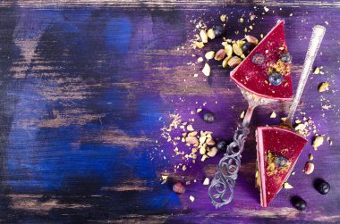 Taze ahududu, yaban mersini, kuş üzümü ve kürek, parlak mor, mavi arka plan antep fıstığı ile lezzetli ahududu kek Parçaları. Metniniz için boş alan.