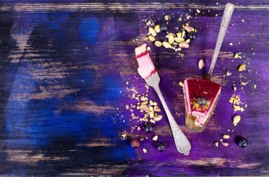 Taze ahududu, yaban mersini, kuş üzümü ve fıstık kürek, parlak mor, mor, mavi arka plan ile lezzetli frambuazlı pasta parçası. Metniniz için boş alan.