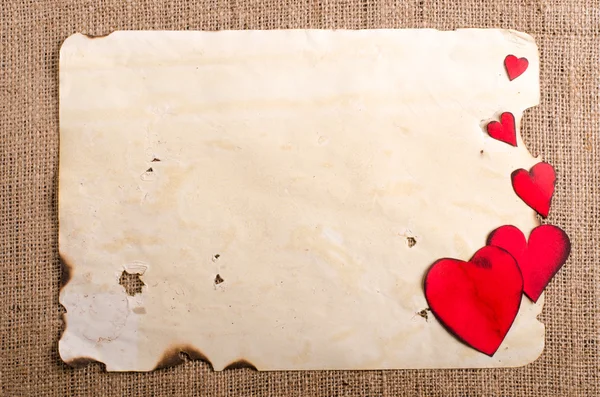 Eski vintage bir kağıt yaprağına, ahşap kalemler ve çuval bezi, çul arka plan üzerinde iki kırmızı kalp. Retro tasarım efektleri. — Stok fotoğraf