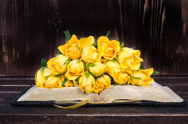 Yellow roses, book on wooden background. Vintage and retro style.