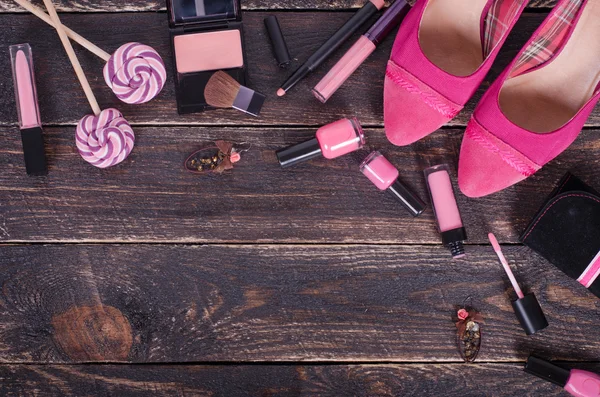 Fondo de las señoras tulipanes rosados, zapatos, lápiz labial, esmalte de uñas, pendientes, rubor, piruletas sobre fondo de madera rosa. Vista superior —  Fotos de Stock