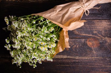 Chamomiles çiçek craft Kağıt ahşap arka plan üzerinde demet. Metniniz için boş alan.