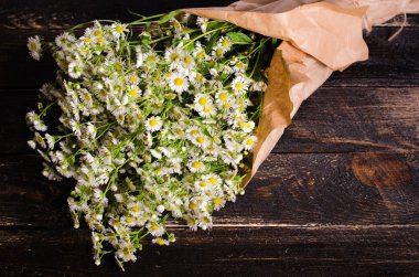 Chamomiles çiçek craft Kağıt ahşap arka plan üzerinde demet. Metniniz için boş alan.