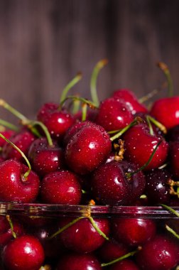 Ahşap bir masa üzerinde bir bardak taze kiraz meyve. Metniniz için boş alan.