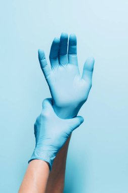 Kadın doktor mavi arka planda tıbbi eldiven takıyor. Uzayı kopyala Ulusal Doktorlar Günü. Uluslararası Hemşireler Günü. Karantina Coronavirus salgını sırasında sağlık ekipmanları.