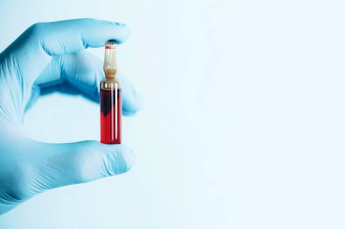 İlaç, iğne, aşı konsepti. Elleri tıbbi eldivenlerde mavi arka planda B vitamini olan ampulleri tutuyor. Uzayı kopyala Karantina Coronavirus salgını sırasında sağlık ekipmanları.