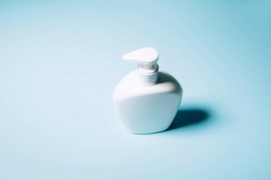 Mavi arka planda beyaz sabun şişesi. Uzayı kopyala Kırpma yolu olan güzellik konteynırını kapat. Salgın sırasında güvenli kalacak ürünler. Covid19 karantina sırasında.