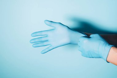 Kadın doktor mavi arka planda tıbbi eldiven takıyor. Uzayı kopyala Ulusal Doktorlar Günü. Uluslararası Hemşireler Günü. Karantina Coronavirus salgını sırasında sağlık ekipmanları.