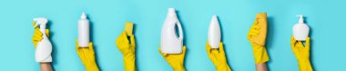 Eldivenli eller mavi arka planda deterjan şişeleri tutuyor. Fotokopi alanı olan pankart. Kimyasal temizlik ürünleri, ev kimyasalları, fırçalar ve malzeme kolajı. Temizlik hizmeti kavramı.