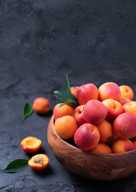 Siyah arka planda olgun kayısılar. Üst görünüm, boşluğu kopyala. Meyve pankartı. Sağlıklı vejetaryen yemekleri, detoks ya da diyet konsepti. Meyve yaz konsepti. Reçel için bir kase hasat edilmiş kayısı..