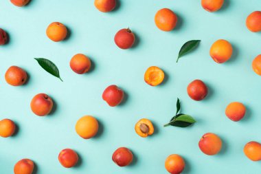 Mavi arka planda kayısı deseni var. Üst manzara, düz yatış. Taze yaz meyvesi konsepti. Yaratıcı tasarım. Sağlıklı vejetaryen yiyecekler, detoks veya diyet konsepti