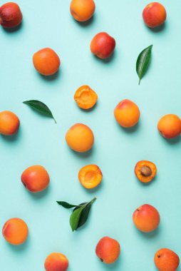 Mavi arka planda kayısı deseni var. Üst manzara, düz yatış. Taze yaz meyvesi konsepti. Yaratıcı tasarım. Sağlıklı vejetaryen yiyecekler, detoks veya diyet konsepti