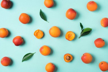 Mavi arka planda kayısı deseni var. Üst manzara, düz yatış. Taze yaz meyvesi konsepti. Yaratıcı tasarım. Sağlıklı vejetaryen yiyecekler, detoks veya diyet konsepti