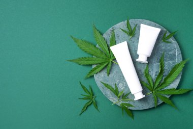 CBD yağlı kozmetik ürünler ve mermer arka planda kenevir yaprakları. Düz konum, kopyalama alanı. Üst Manzara. Doğal cilt bakımı. Kenevir yağı ve marihuana yapraklı krema..