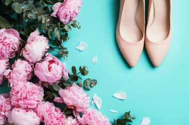 Bej kadın ayakkabıları çıplak ayakkabılar, pembe şakayıklar, mavi arka planda okaliptüs çiçeği. Düz yerde, üst tarafta. Uzayı kopyala Çiçek modeli. Düğün, doğum günü, yıldönümü buketi. Kadın günü, Anneler günü..